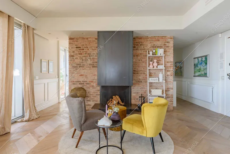 Poltrone di design nel salotto con camino e parete in mattoncini rossi a vista