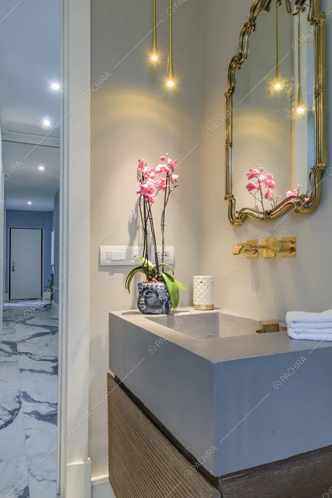 Dal bagno, con lavabo in pietra e mobile in legno, vista sul corridoio e sulla porta d'ingresso bianca
