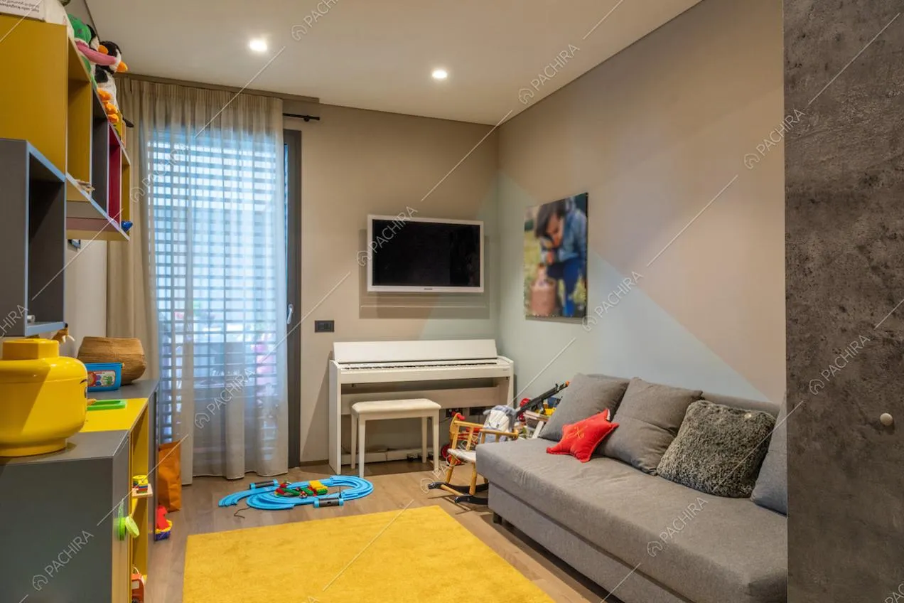 Sala giochi con pavimento in parquet e divano marrone e pianola bianca