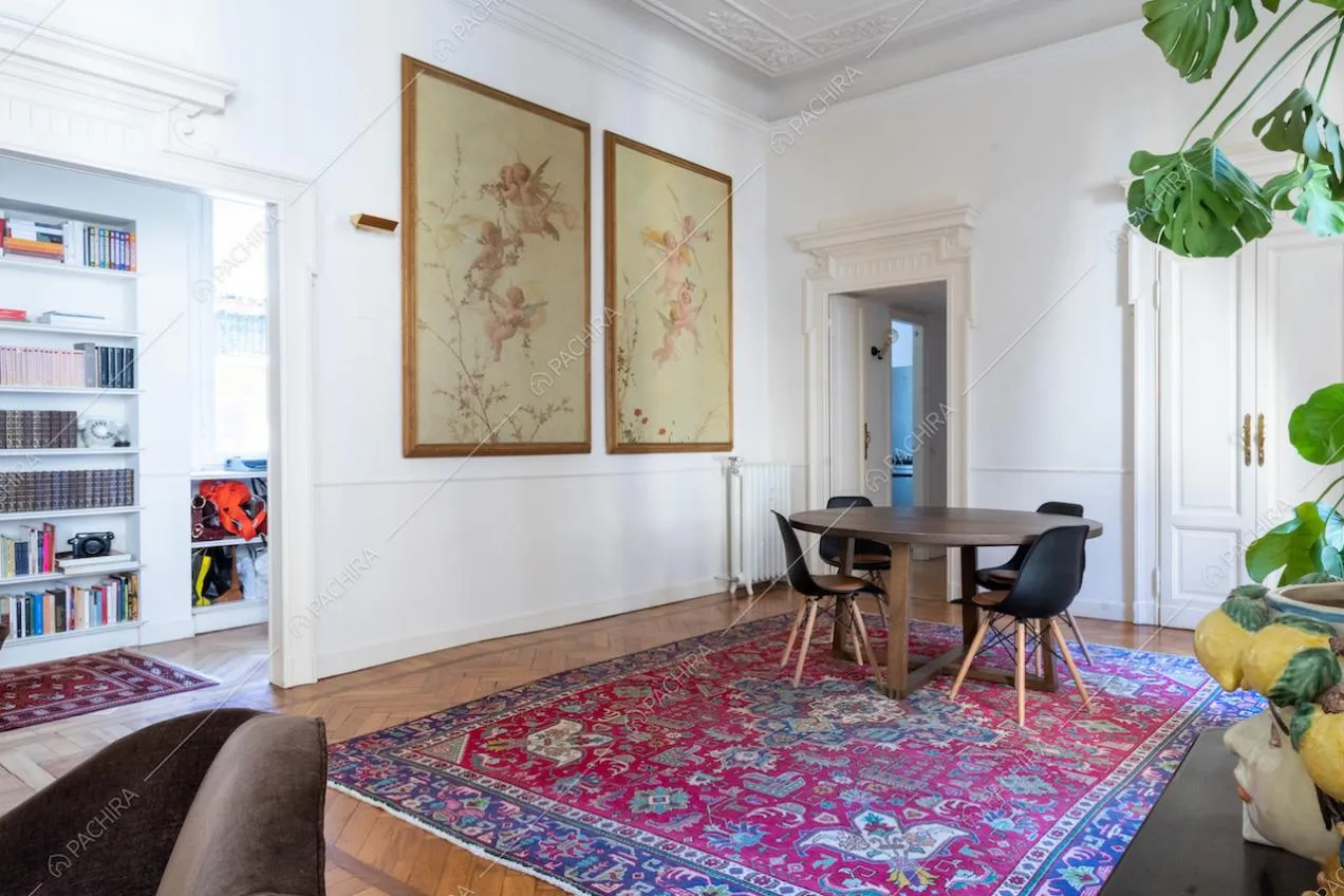Dal salotto con boiserie sul soffitto vista sul tavolo da pranzo in legno e sulla camera da letto