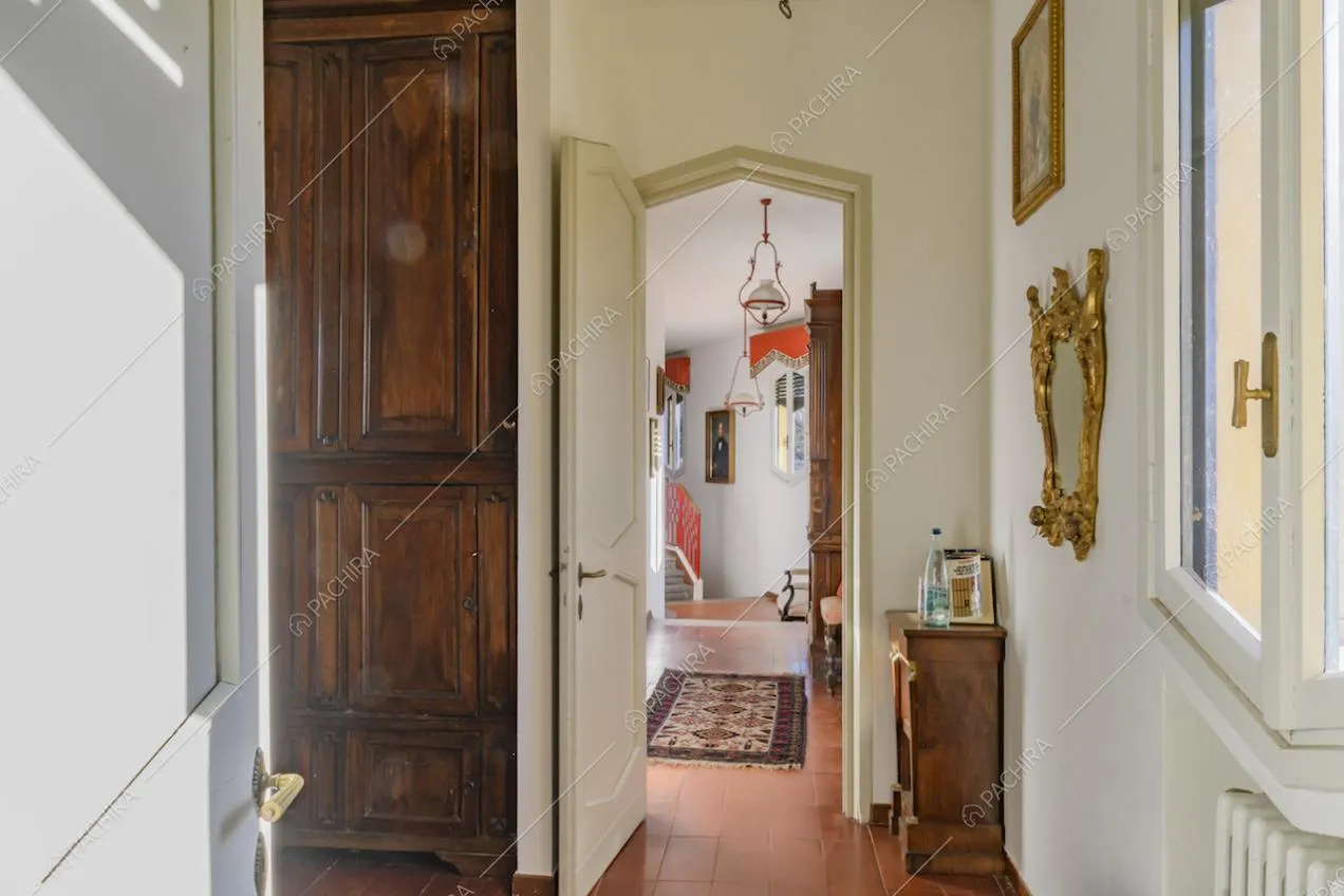 Corridoio con pavimento in cotto con accesso alle scale e scorcio sulla ringhiera rossa