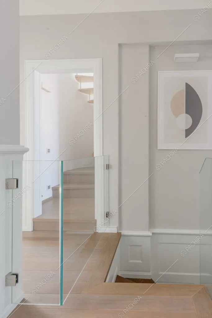 Pavimento in parquet nel pianerottolo con ringhiera in vetro e pareti grigie