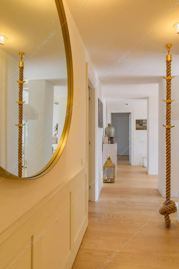 Lungo corridoio con specchio rotondo, boiserie alle pareti e pavimento in parquet