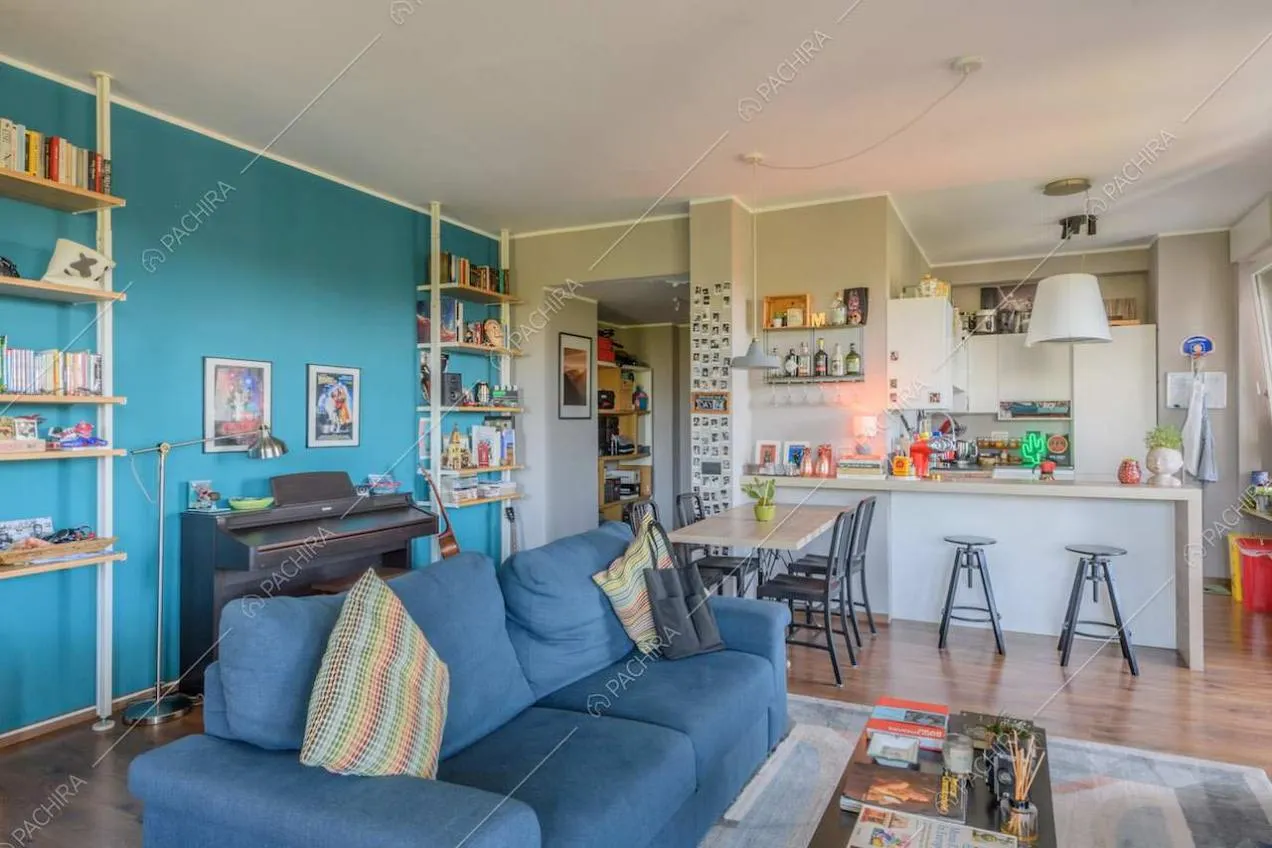 Divano blu nella zona living con parete azzurra e pavimento in parquet