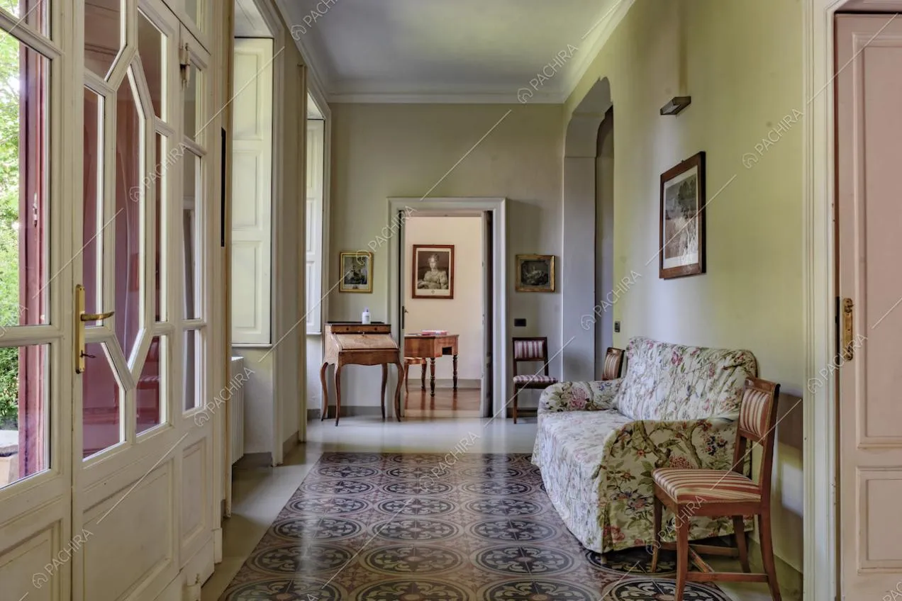 Ingresso della location, tramite porta a vetri bianca, nell'ampio corridoio dalle pareti verdi e con boiserie sul soffitto
