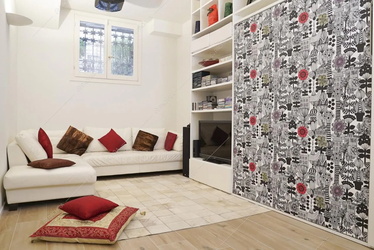 Salottino con parete decorata, mobile bianco e televisore