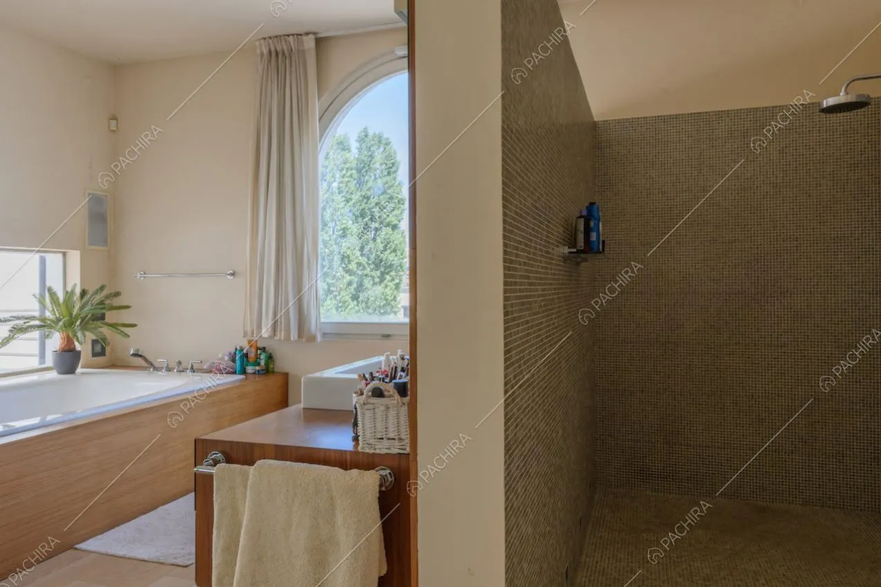 Grande box doccia e vasca nel luminoso bagno con pavimento in parquet