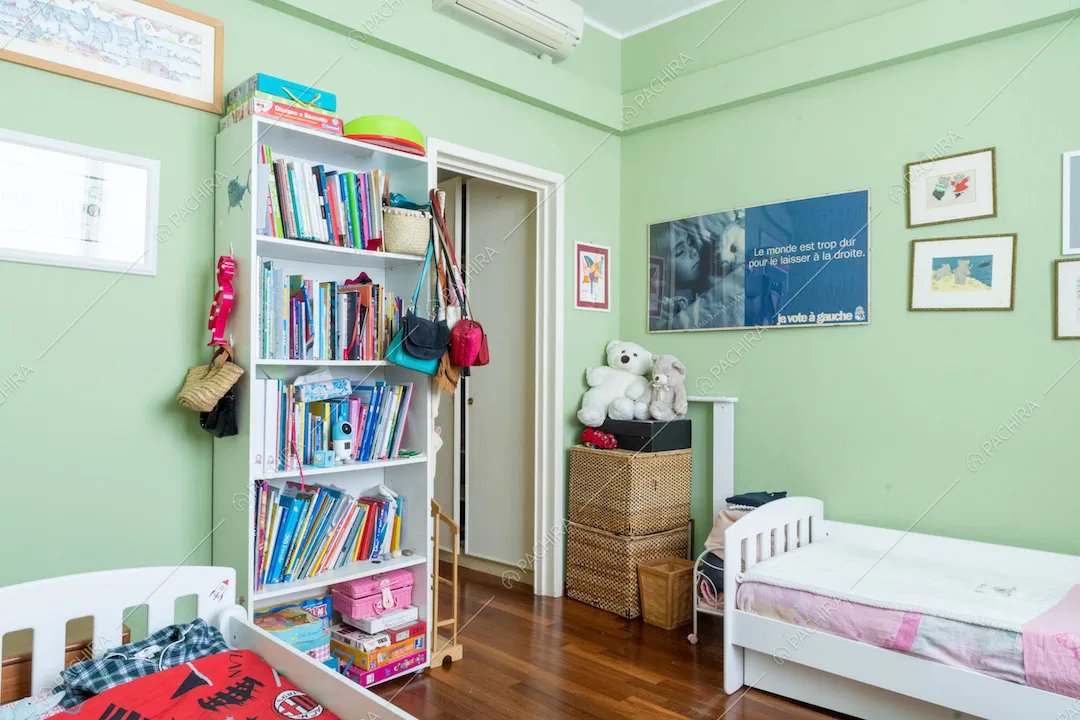 Boiserie alle pareti verdi della camera da letto da bambini con pavimento in parquet