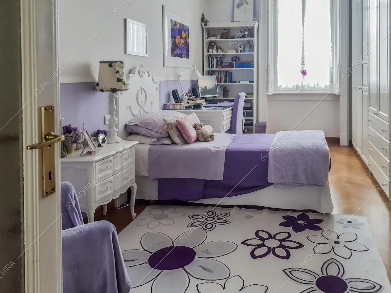 Camera da letto arredata nei toni del viola e tappeto a fantasia floreale