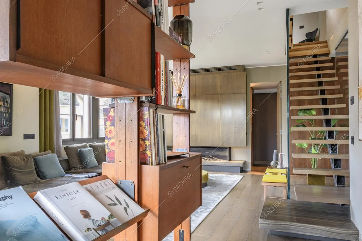 Scala con gradini sospesi e libreria in legno nella zona giorno