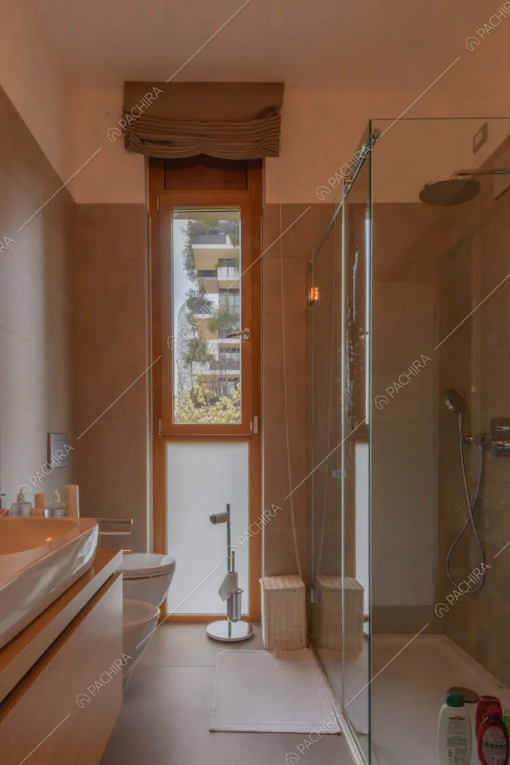 Bagno con box doccia e piastrelle grigie su pavimento e pareti