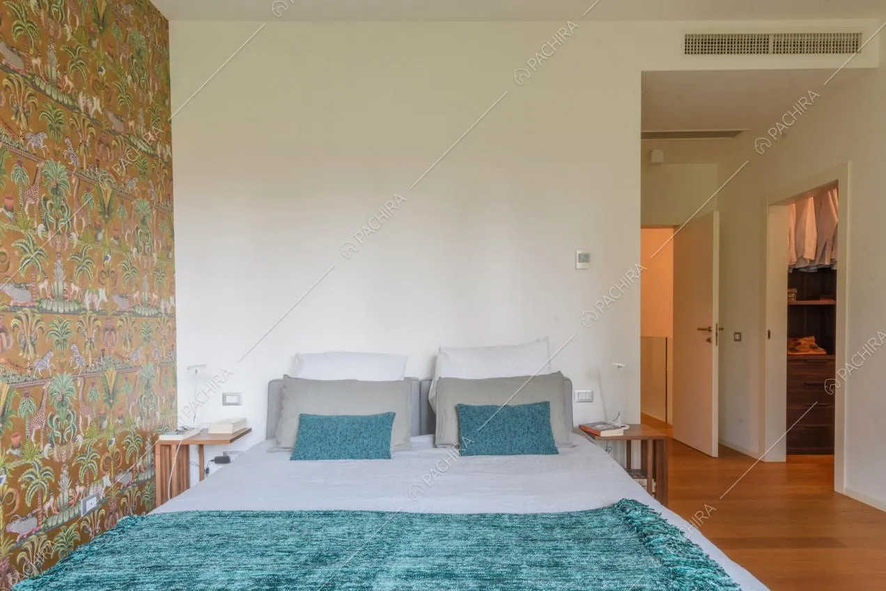 Luminosa camera da letto matrimoniale con carta da parati e cabina armadio