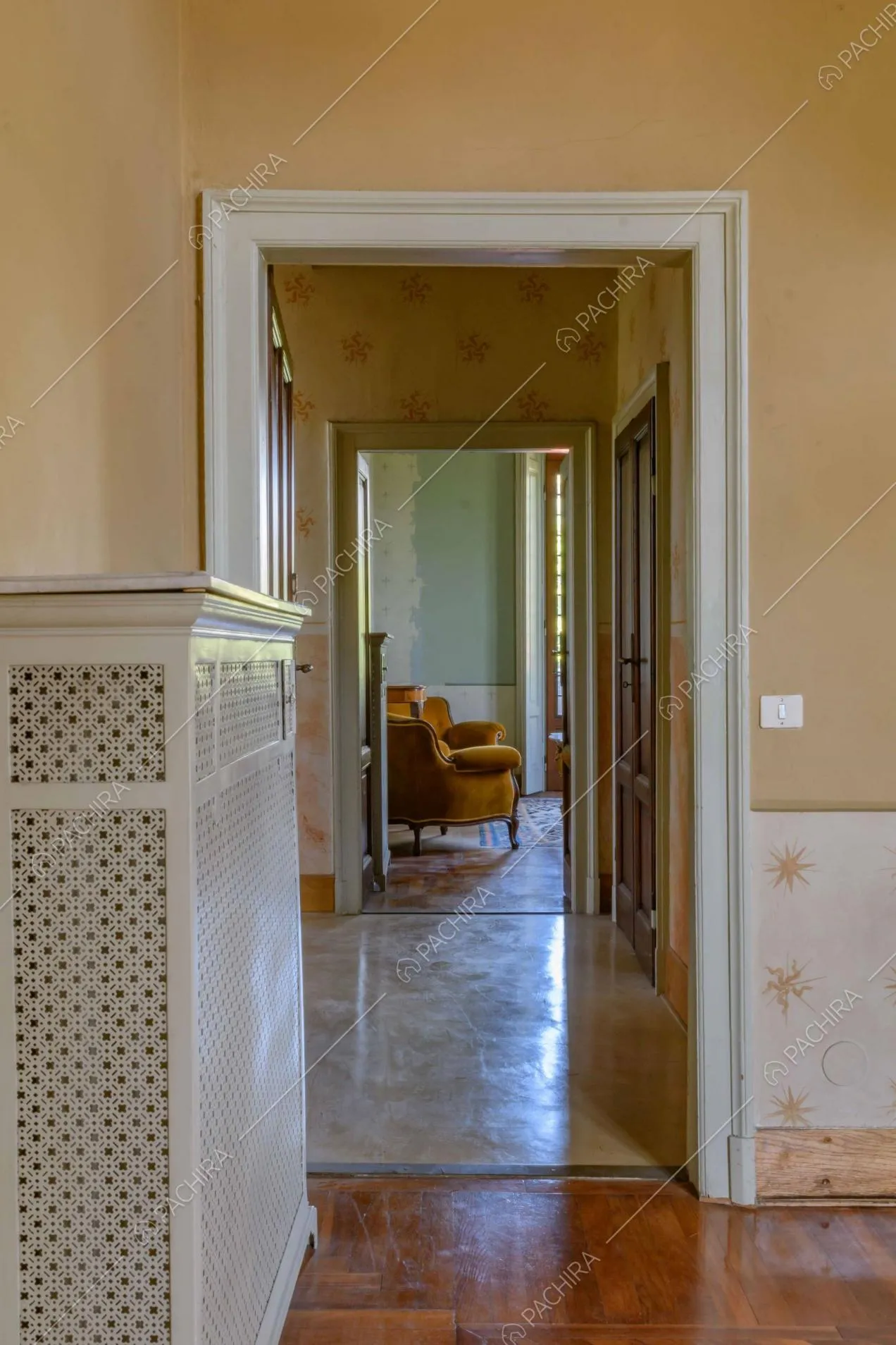 Dall'atrio vista sul salotto dalle pareti verdi con poltrone in velluto e pavimento in parquet