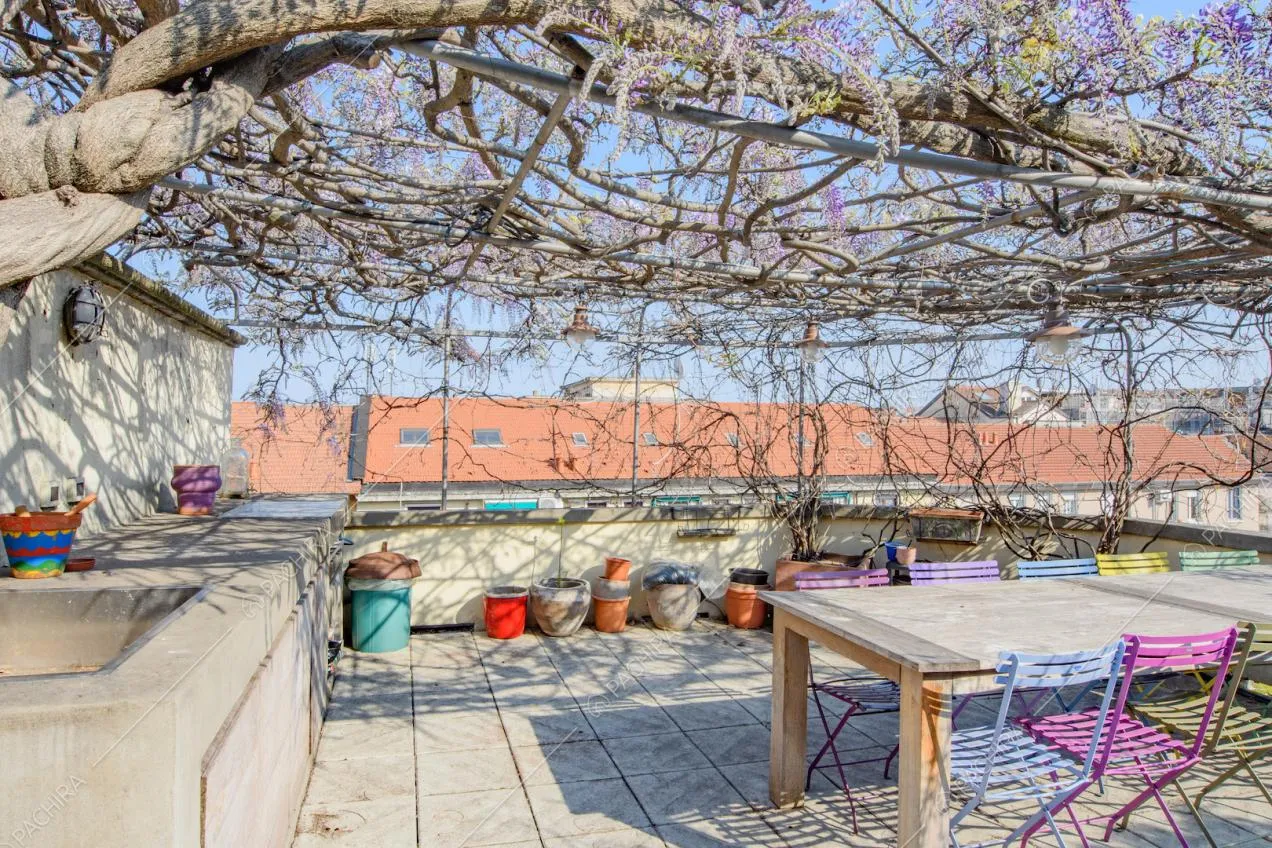 Tavolo da pranzo e sedie colorate in metallo sulla terrazza con tetto in glicine