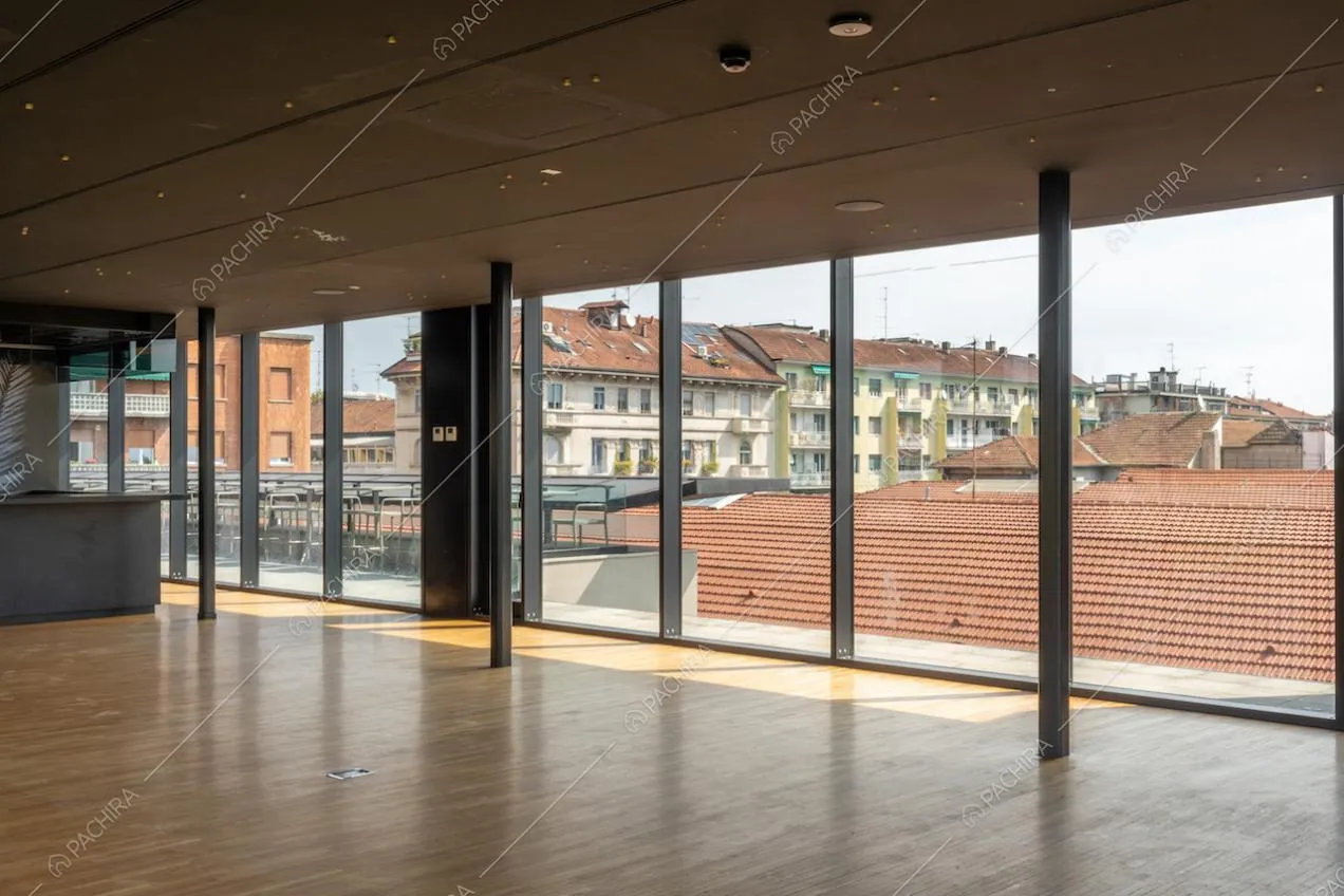 Salone con vista sullo skyline di Milano attraverso le grandi vetrate e pavimento in parquet