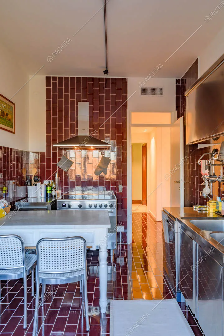 Cucina a parete con pavimento e pareti in piastrelle rosse, fornelli a induzione e tavolo da pranzo