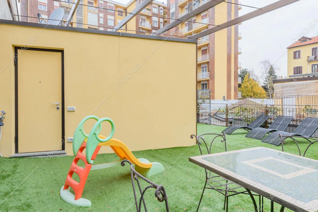 Terrazza con erba finta sul pavimento e vista sugli esterni gialli