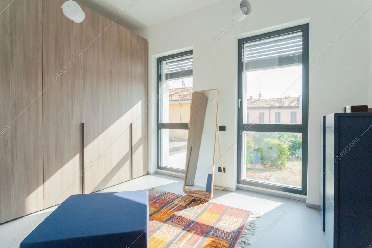 Ampia e luminosa cabina armadio con armadi in legno, pouf blu e specchio
