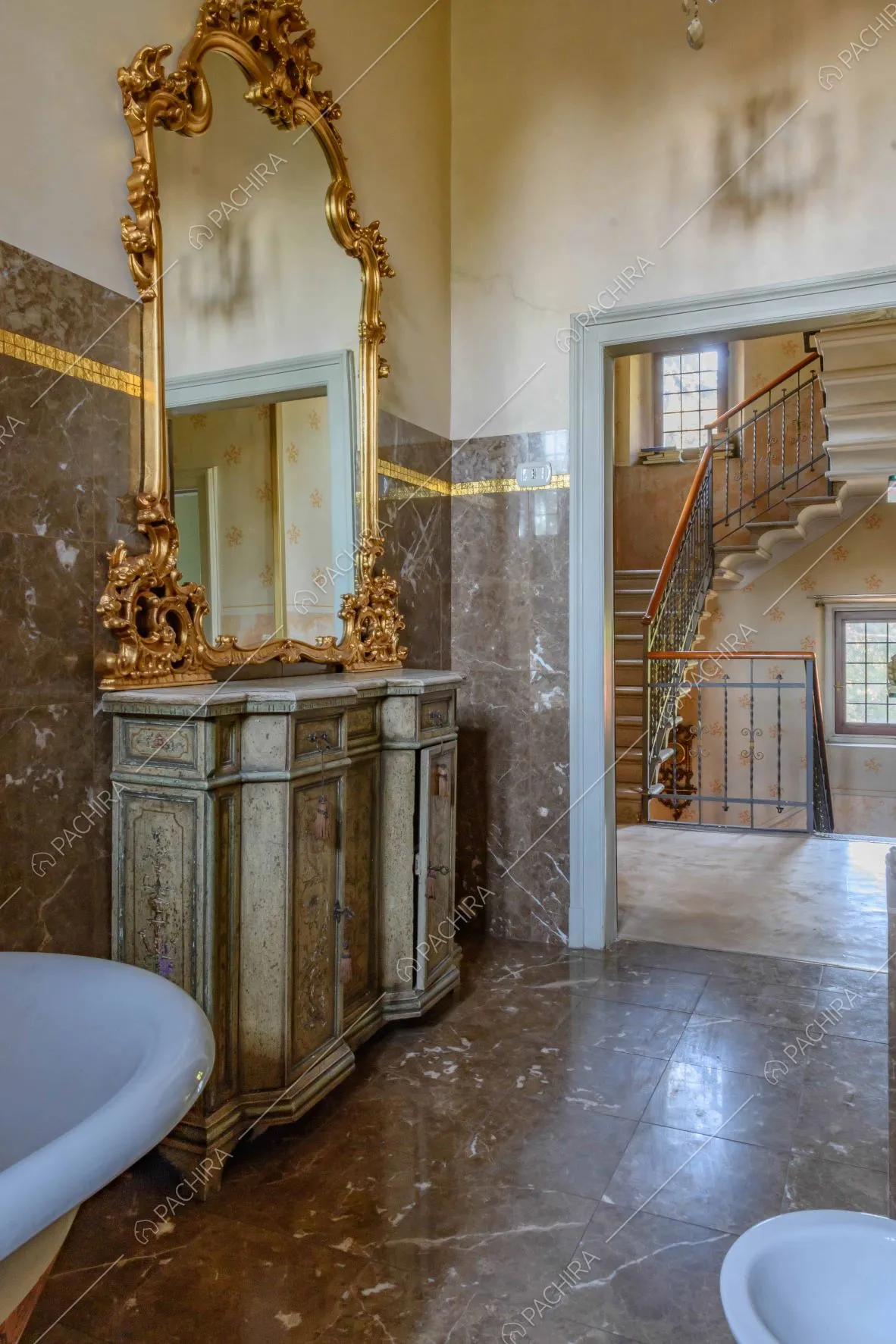 Dal bagno con le pareti e il pavimento in marmo marrone vista sulle scale