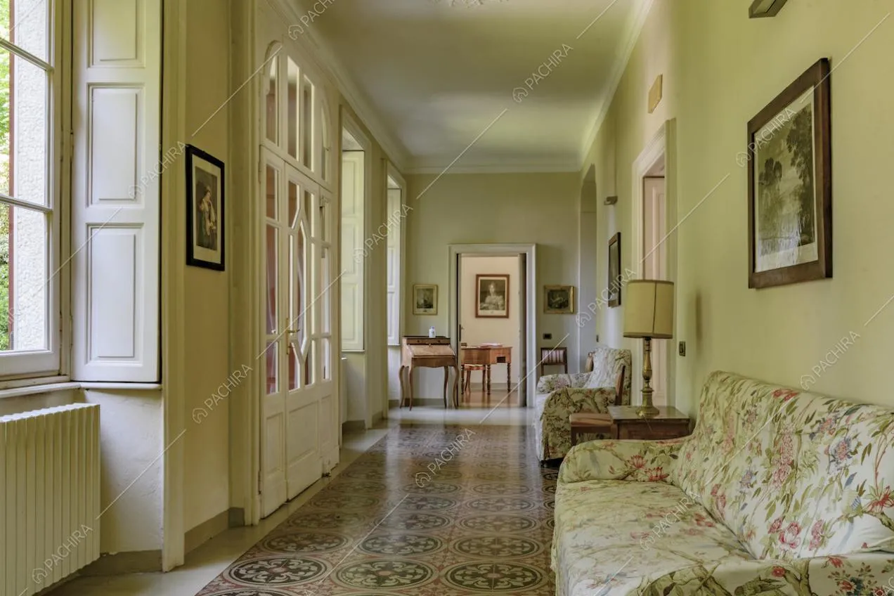 Corridoio con pavimento in marmo, porte-finestre bianche e boiserie sul soffitto