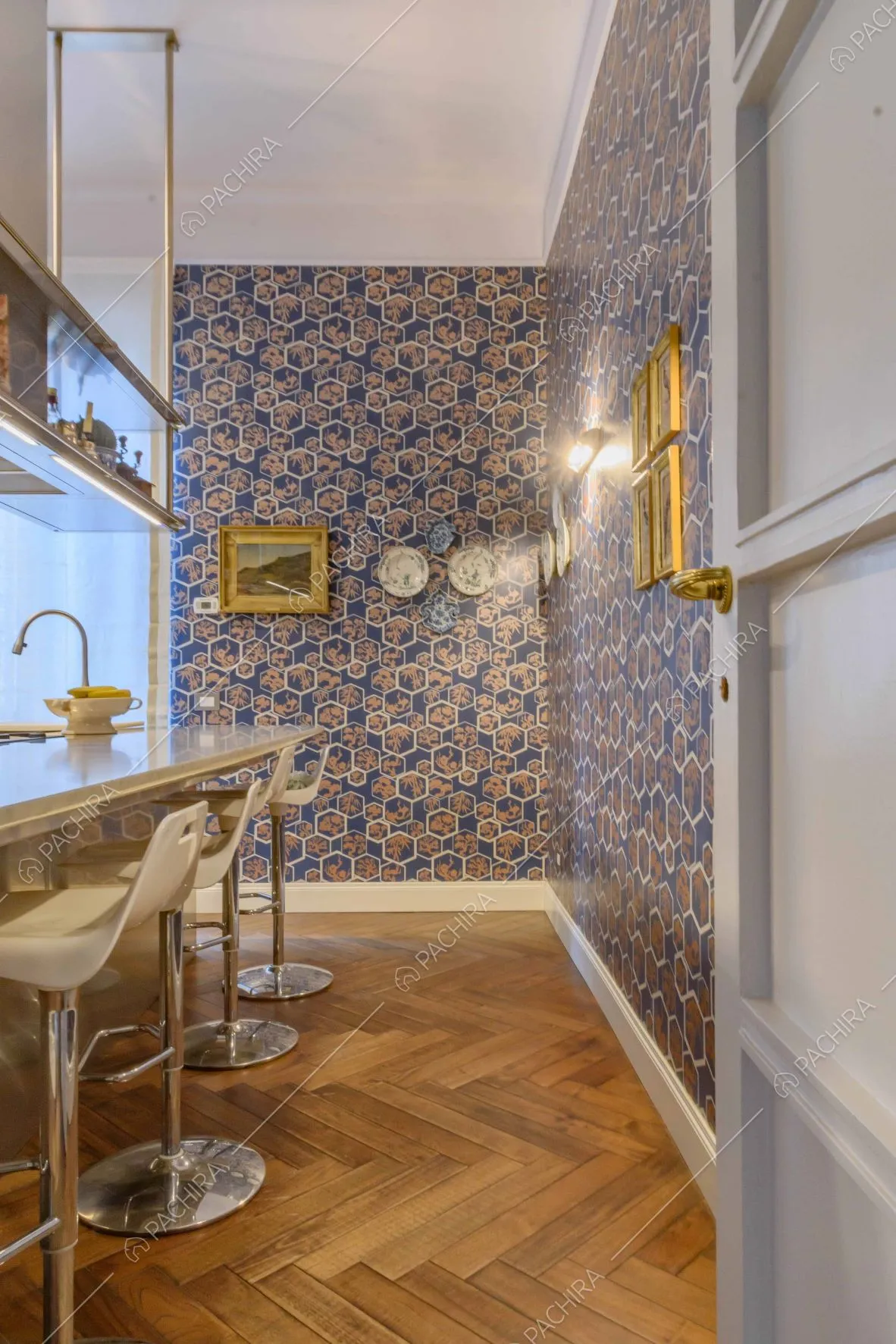 Cucina a isola con bancone e sgabelli, pavimento in parquet a spina di pesce e carta da parati
