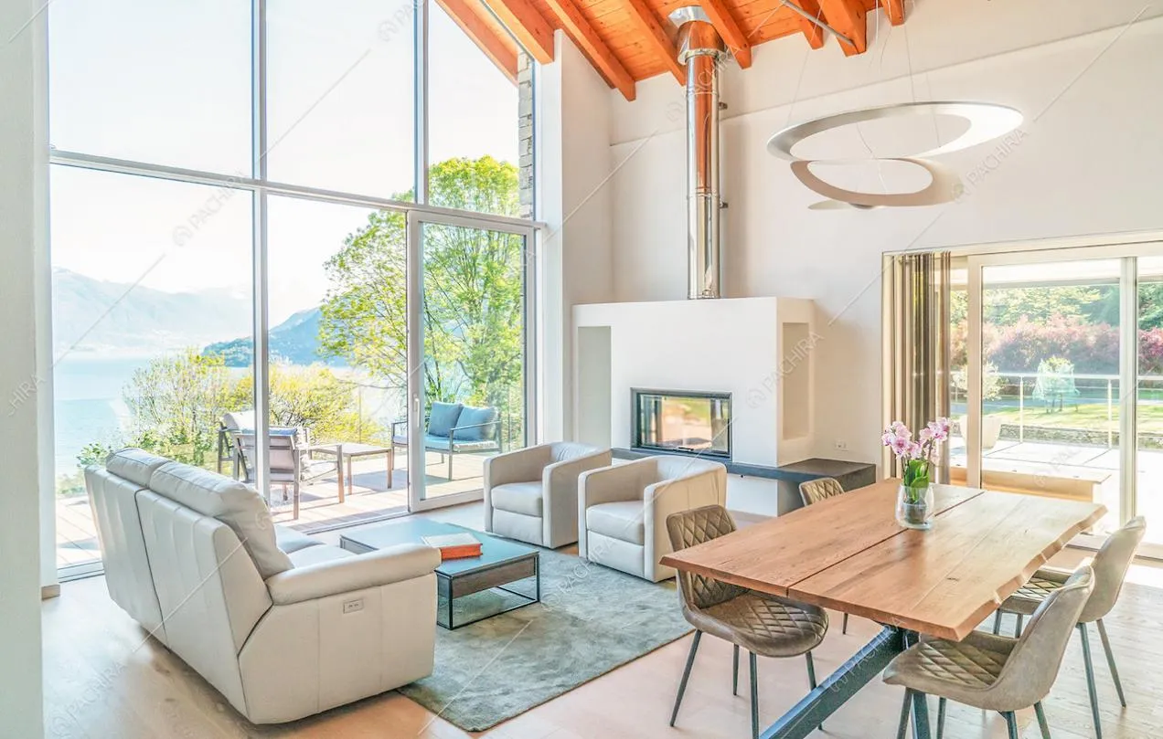 Salotto con pavimento in parquet, travi in legno a vista sul soffitto e porte-finestre per accedere alla terrazza