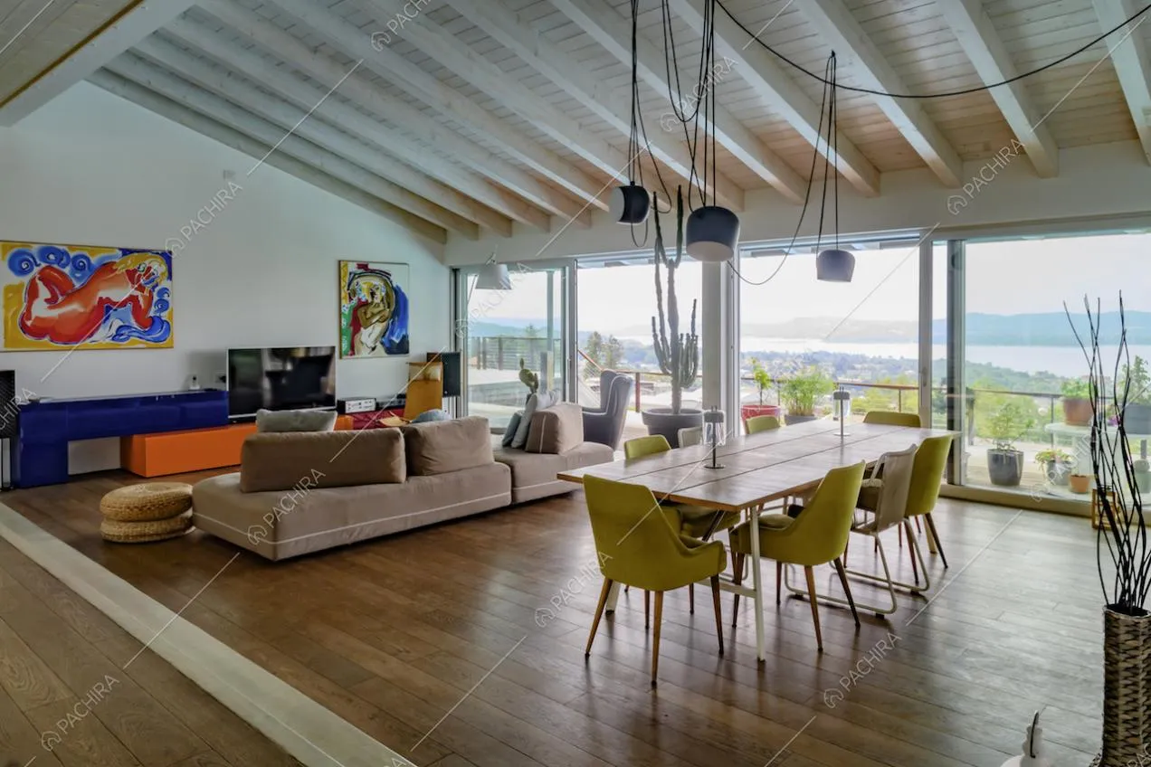 Nella sala con pavimento in parquet, tavolo da pranzo, divani e porte-finestre scorrevoli per accedere alla terrazza