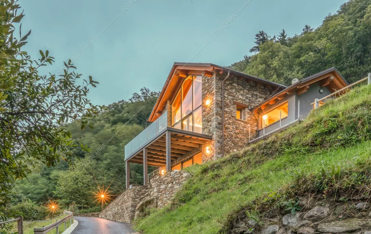 Dal giardino vista sulla villa con esterni in pietra, ampie vetrate e terrazza