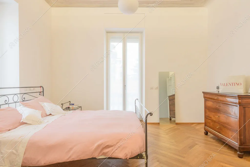 Pavimento in parquet a spina di pesce nella luminosa camera da letto matrimoniale