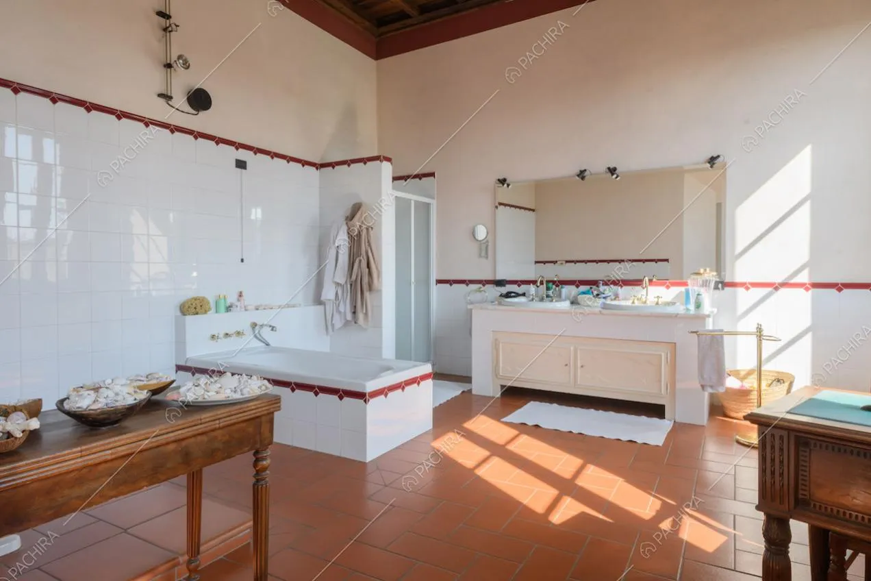 Grande bagno con vasca, pareti rosa e in piastrelle bianche