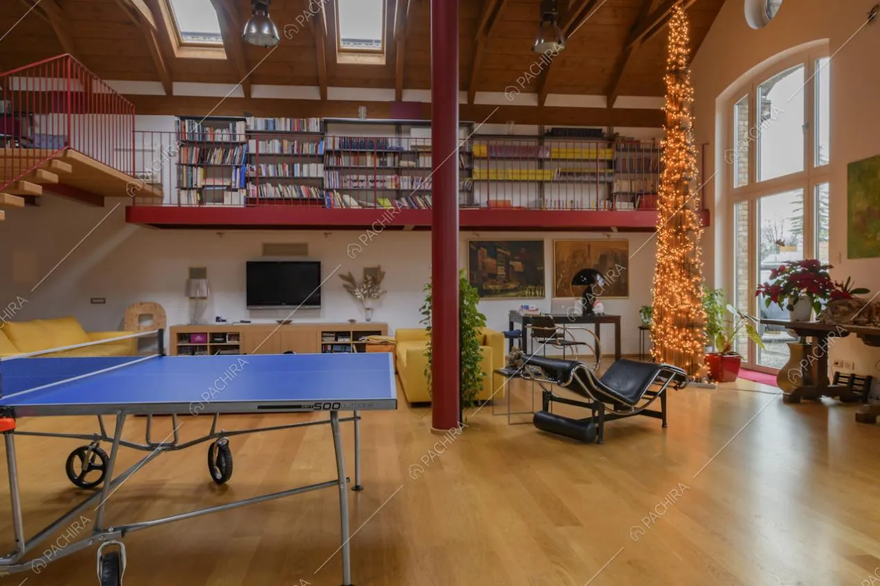 Luminoso salone con pavimento in parquet, colonna rossa e vista sulla libreria del soppalco