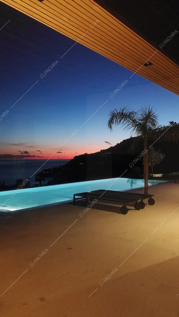 Terrazza al tramonto con piscina a sfioro vista mare illuminata