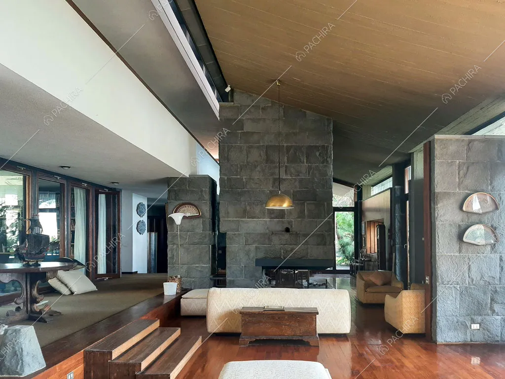 Pavimento in parquet, pareti in pietra a vista e grandi vetrate nella zona living