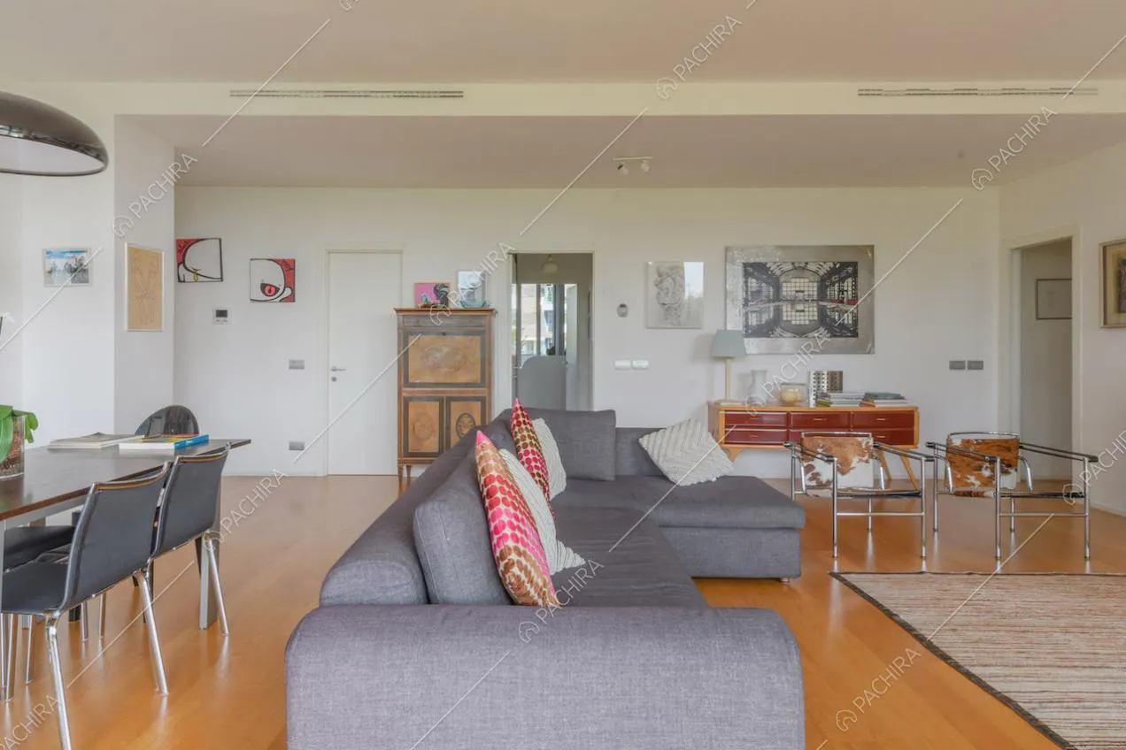 Divano grigio angolare nella luminosa zona living con pavimento in parquet