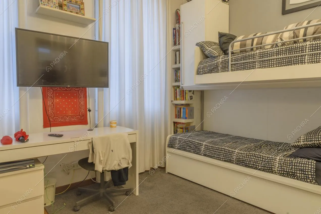 Camera con letto a castello bianco e scrivania  