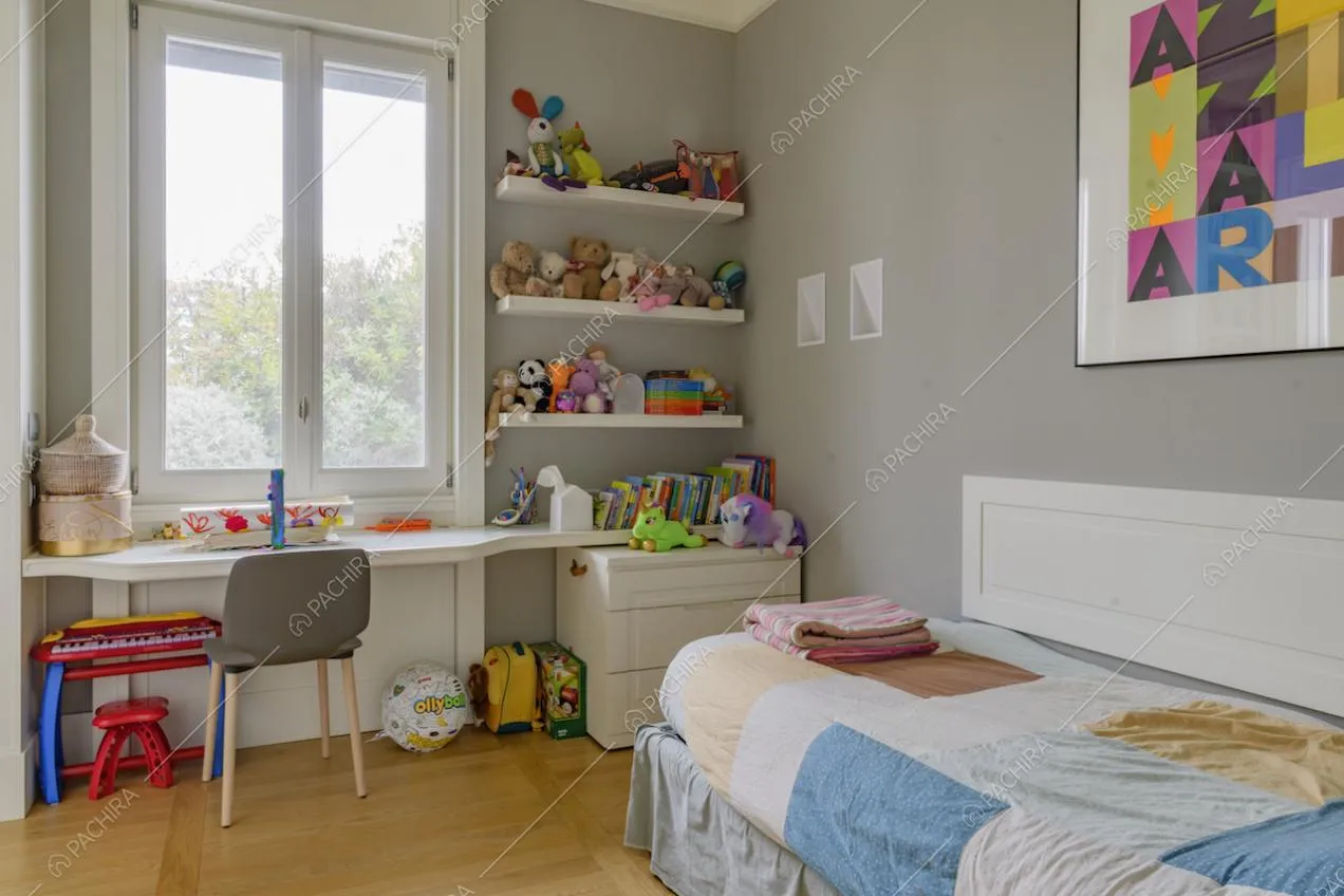 Camera da letto da bambini dalle pareti grigie, con scrivania bianca e pavimento in parquet