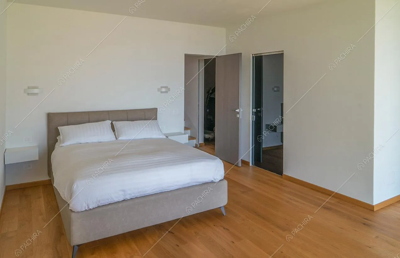 Camera da letto matrimoniale minimal con pavimento in parquet, pareti bianche e bagno privato