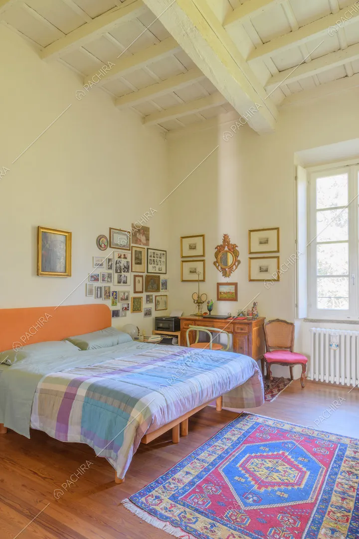 Letto matrimoniale nella camera con pavimento in parquet e soffitto a cassettoni bianco