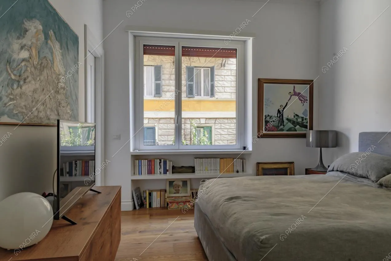 Camera da letto matrimoniale con finestra, pavimento in parquet e mobile tv in legno