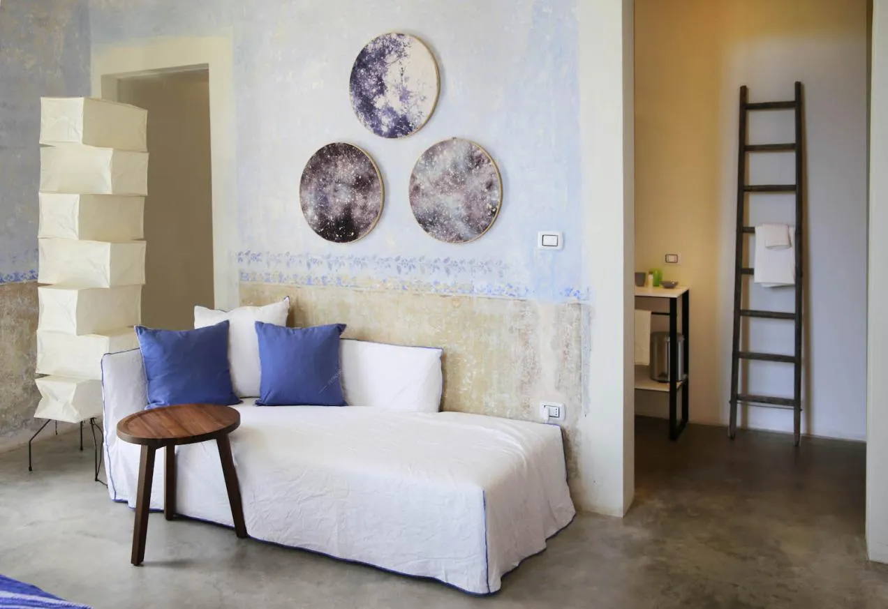 Luminoso atrio con pouf bianco e pareti délabré azzurre e arancioni