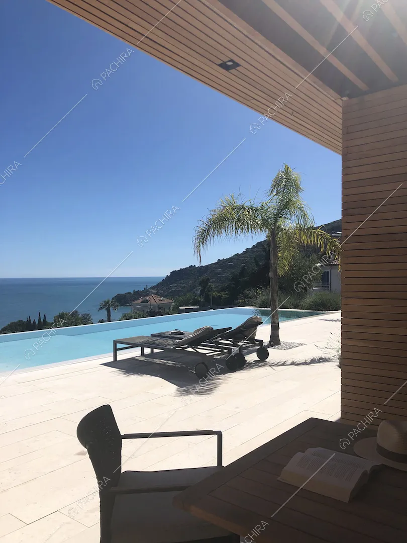 Dal tavolo da pranzo sulla veranda con soffitto in travi in legno, vista sulla piscina e sul mare