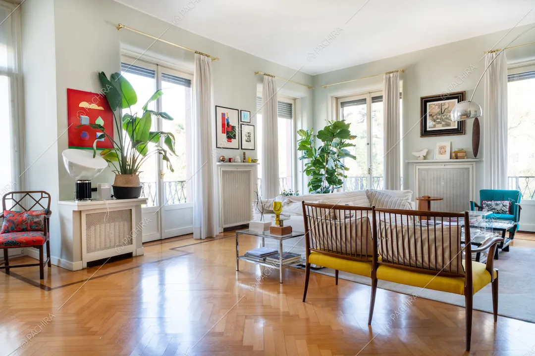 Salotto con pavimento in parquet a spina di pesce e porte-finestre per accedere al balcone
