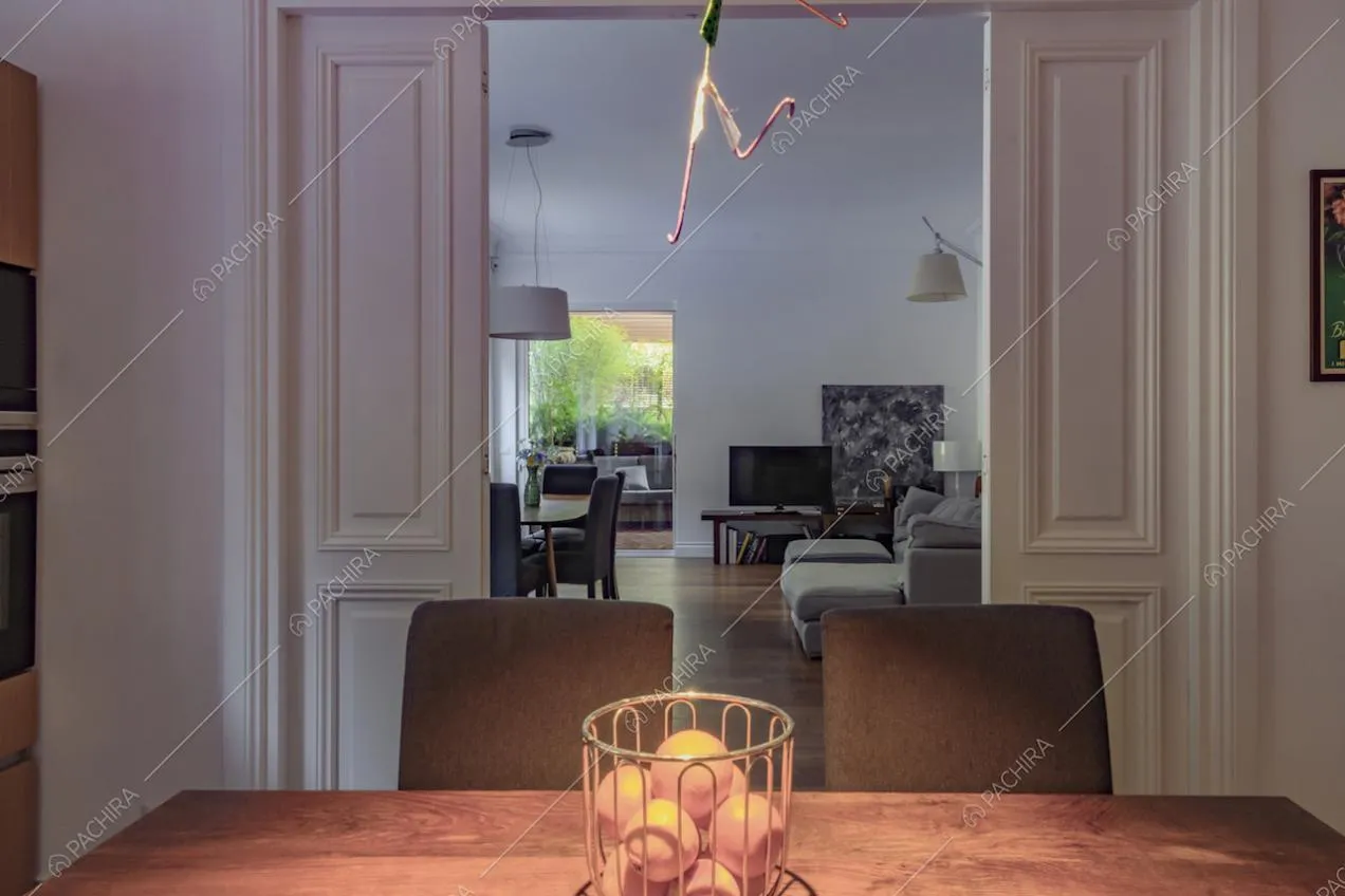 Dal tavolo da pranzo in legno della cucina vista sulla sala separata dalle porte bianche con boiserie