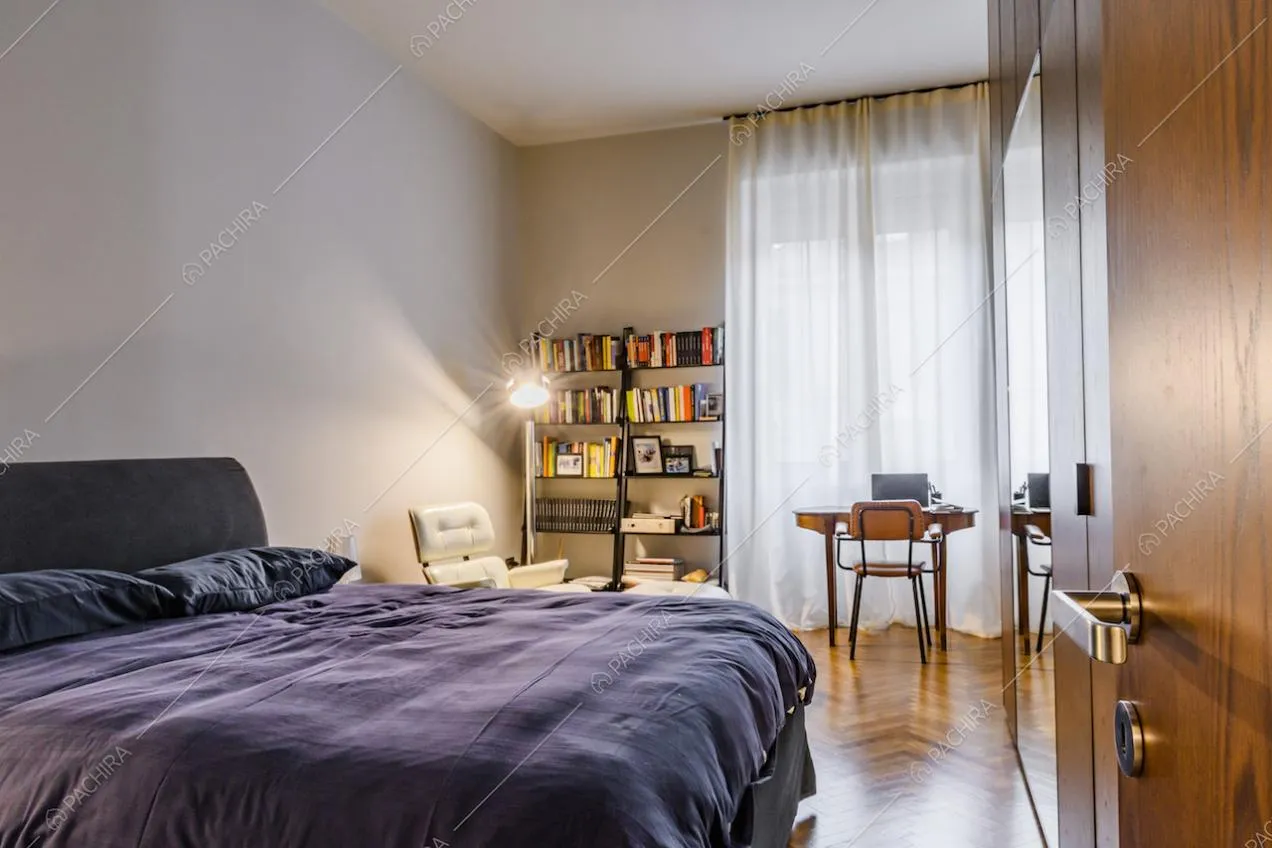 Camera da letto padronale con ampia finestra e tende bianche