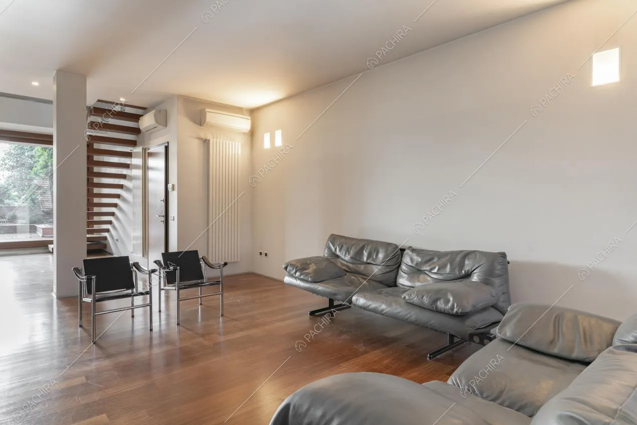 Divani in pelle grigi, pareti bianche e parquet