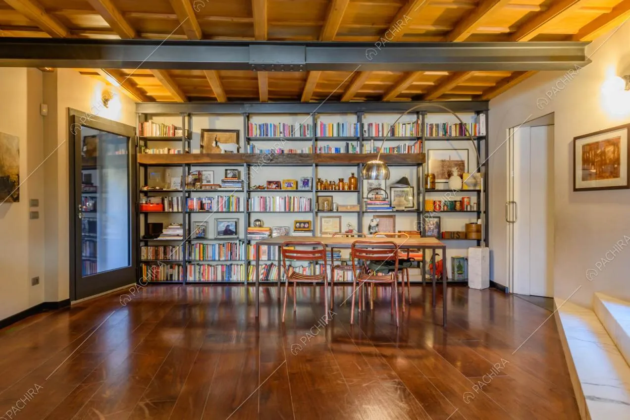 Tavolo da pranzo nella sala con pavimento in parquet e libreria