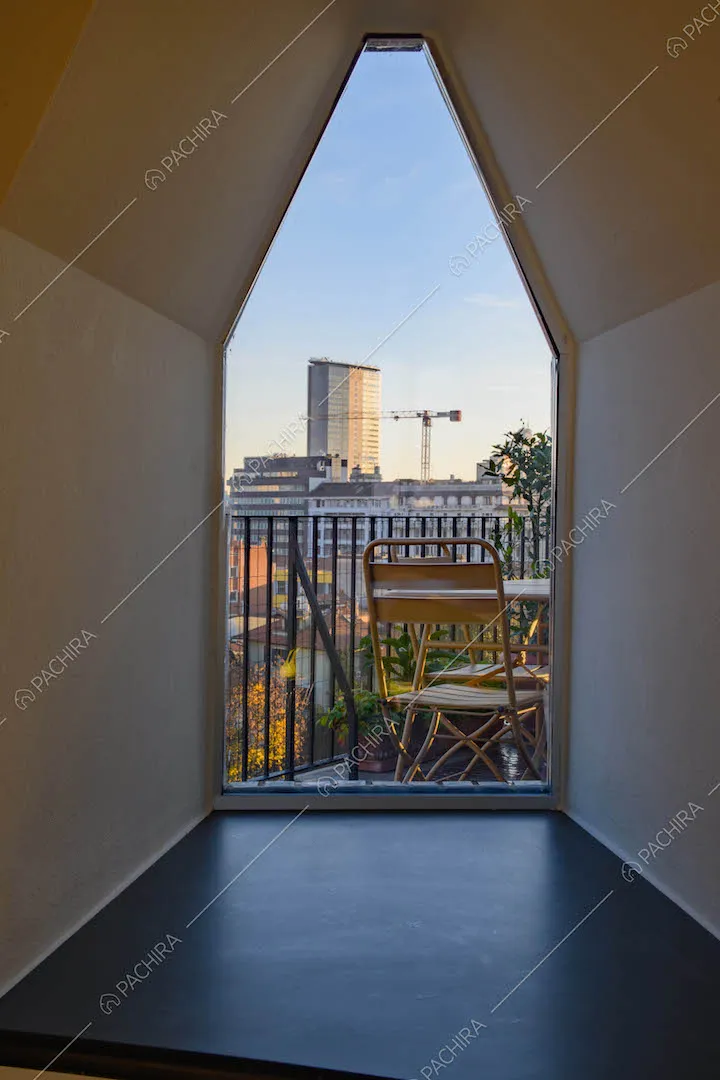 Corridoio dal pavimento nero con finestra esagonale che si affaccia sulla terrazza