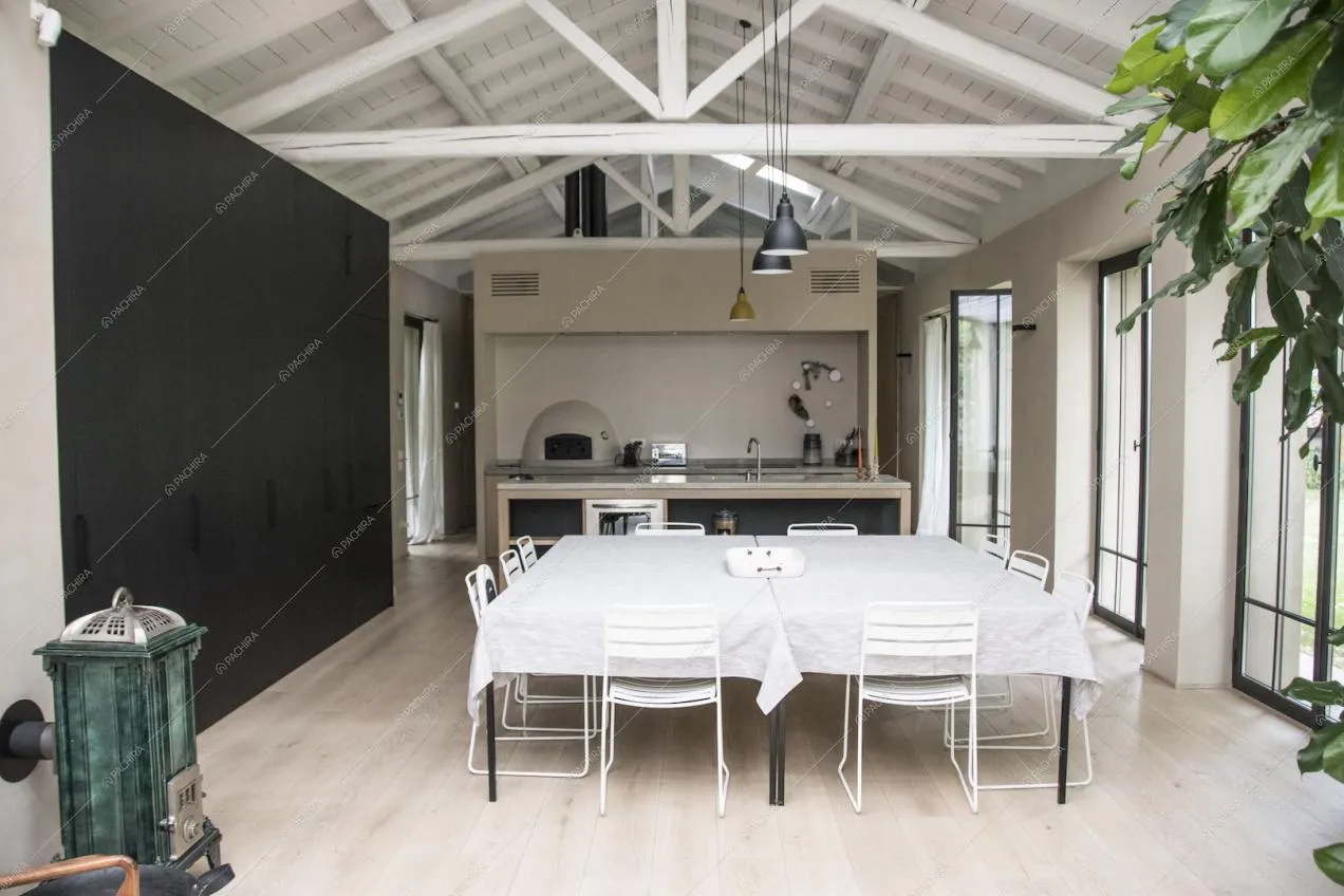 Tavolo da pranzo con sedie, pavimento in parquet e travi a vista bianche