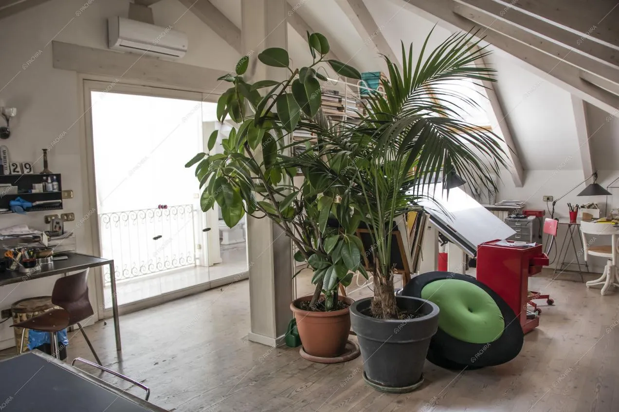 Studio nel solaio con travi a vista, pavimento in parquet e porta a vetri