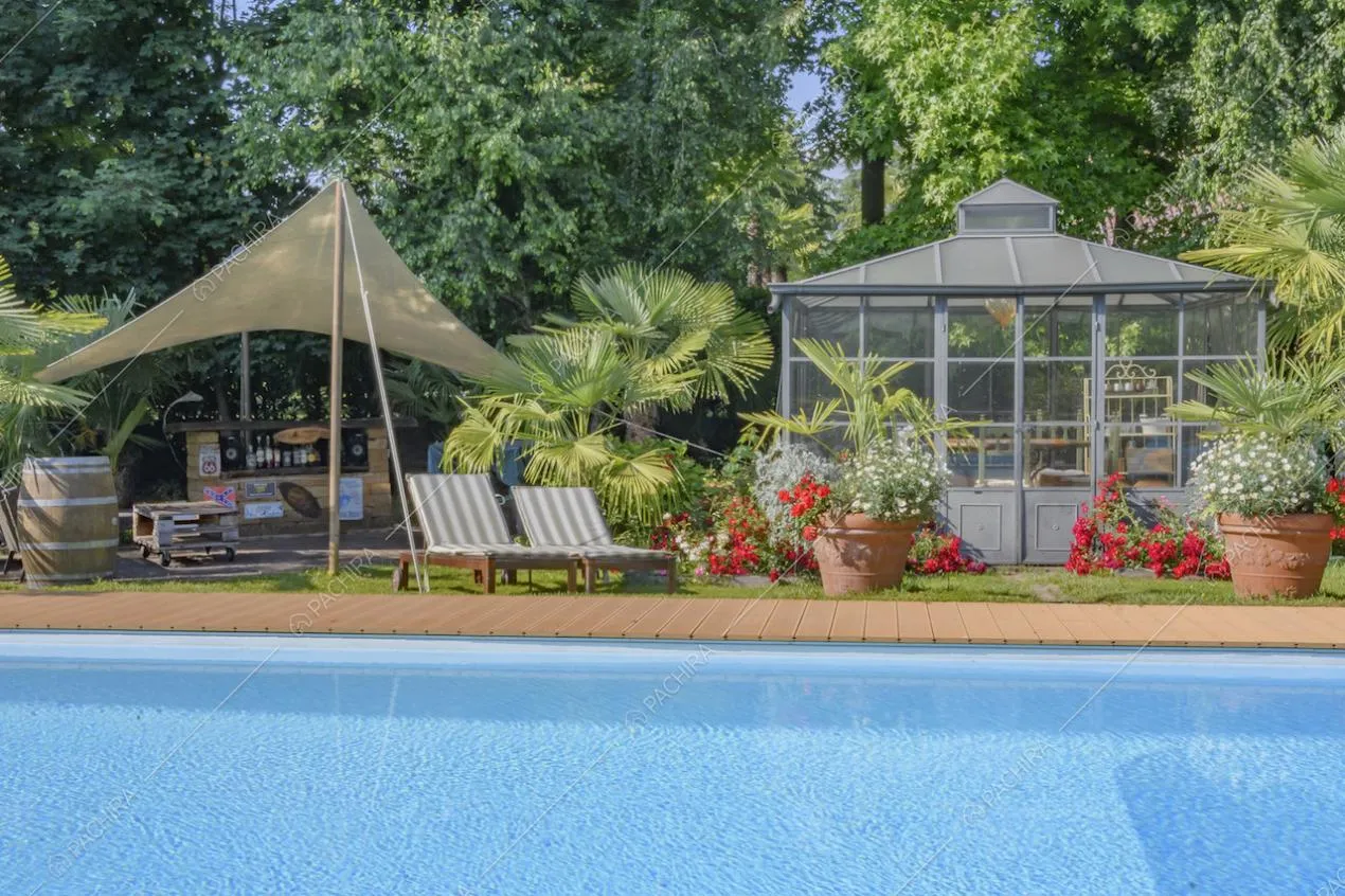 Serra in vetro con fiori e piante in vaso sul bordo della piscina